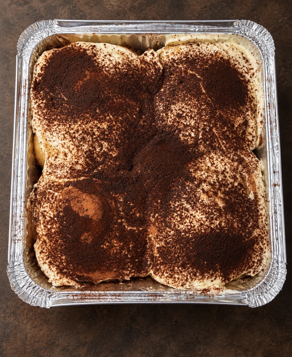 A full tray of No Crumbs tiramisu rolls topped with creamy frosting and cocoa